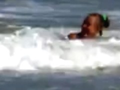 Topless legal age teenager playing at beach in water